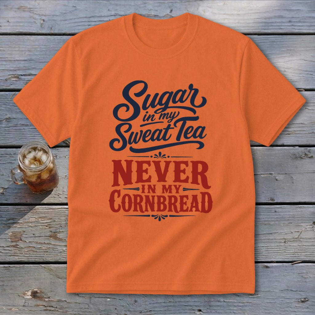 An orange t-shirt featuring the text Sugar in my Sweat Tea, NEVER IN MY CORNBREAD on a wooden background.
