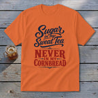 An orange t-shirt featuring the text Sugar in my Sweat Tea, NEVER IN MY CORNBREAD on a wooden background.