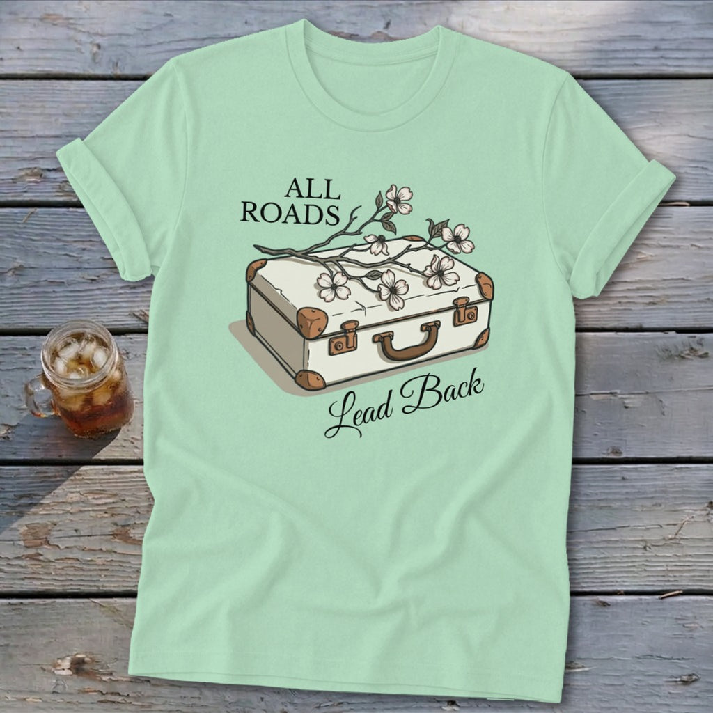 Light mint t-shirt with illustration of suitcase and flowers, text "All Roads Lead Back".