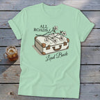 Light mint t-shirt with illustration of suitcase and flowers, text "All Roads Lead Back".