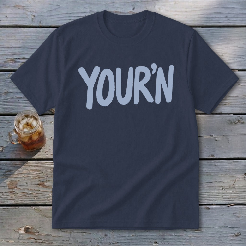 Navy t-shirt with light blue "YOUR'N" graphic, next to a glass of iced tea.