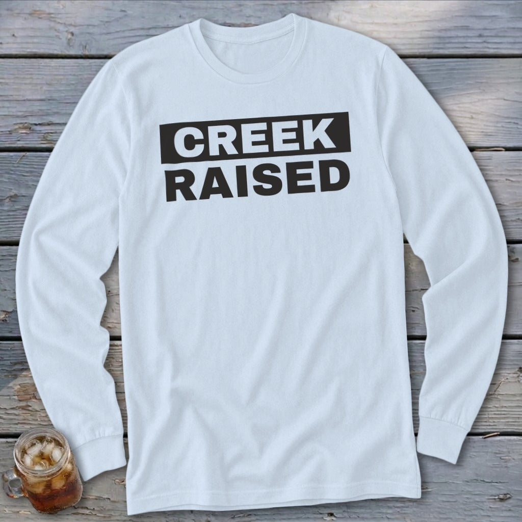 White long-sleeve shirt with black text reading "CREEK RAISED."