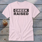 Light pink t-shirt with "CREEK RAISED" in black text.