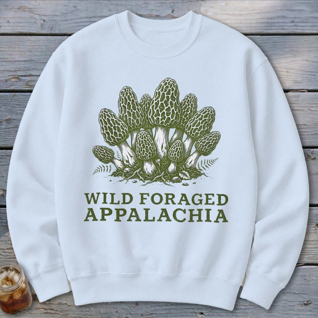 White sweatshirt with a green illustration of morel mushrooms and ferns, text reads "WILD FORAGED APPALACHIA".