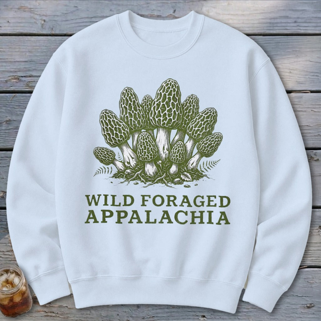 White sweatshirt with a green illustration of morel mushrooms and ferns, text reads "WILD FORAGED APPALACHIA".