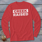 Red long-sleeve shirt with white text "CREEK RAISED" on a white rectangle.