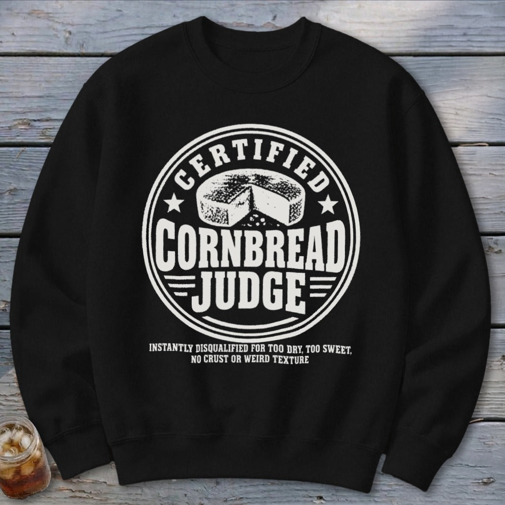 Black crewneck sweatshirt featuring a white circular graphic with cornbread and the text Certified Cornbread Judge.