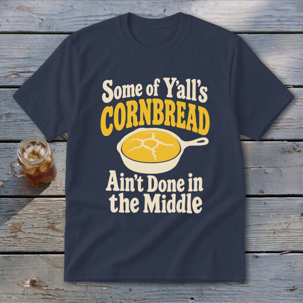 Navy blue t-shirt featuring the text "Some of Y'all's Cornbread Ain't Done in the Middle" above and below a skillet of cornbread.