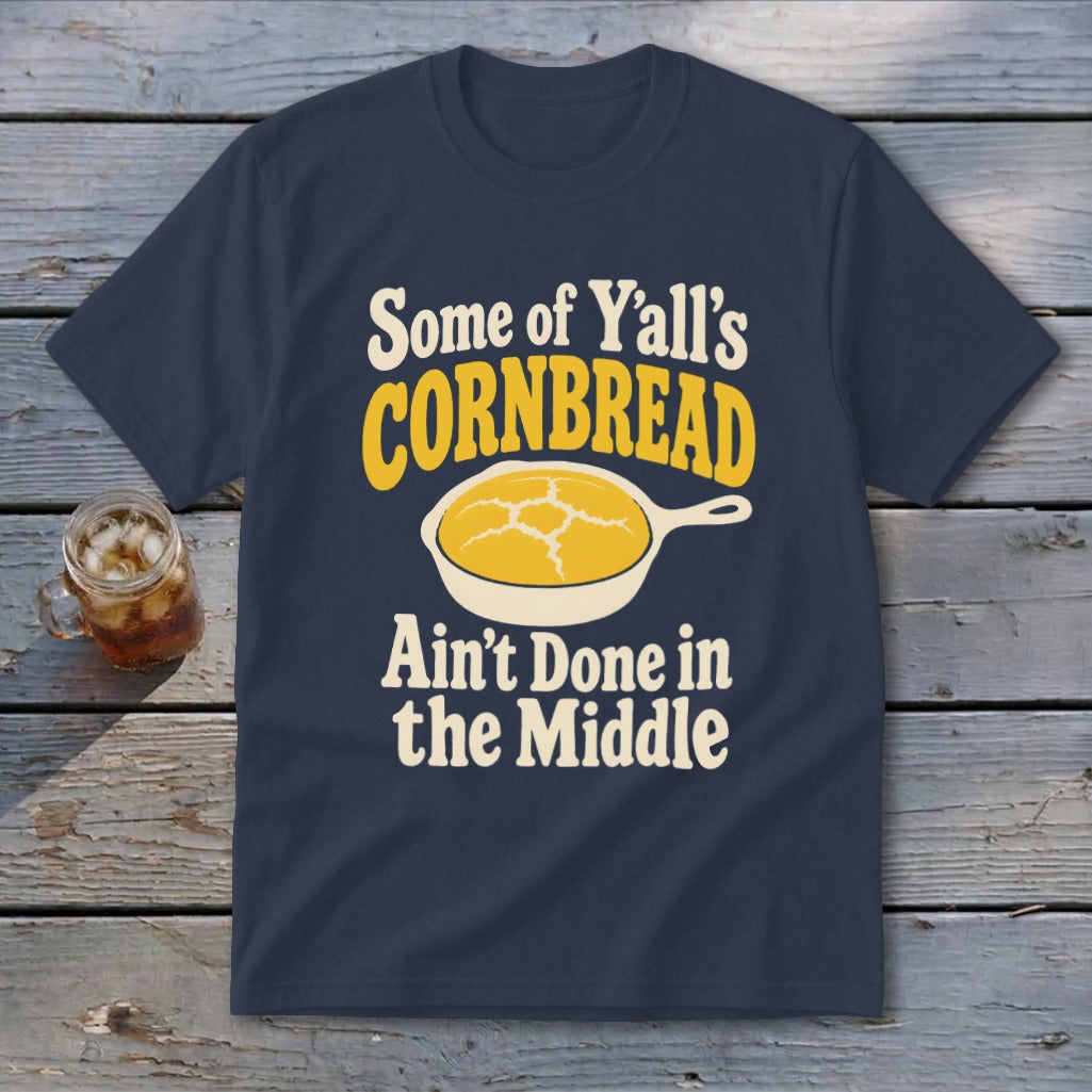 Navy blue t-shirt featuring the text "Some of Y'all's Cornbread Ain't Done in the Middle" above and below a skillet of cornbread.