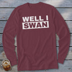 Maroon long-sleeved t-shirt with white text reading WELL I SWAN on a wooden background.