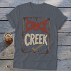 T-shirt with a distressed sign graphic reading "CRICK" crossed out and "CREEK" checked.