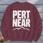 Maroon crewneck sweatshirt featuring white text that reads PERT NEAR above a simple mountain outline.