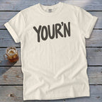Cream Comfort Colors t-shirt with "YOUR'N" printed in dark gray.