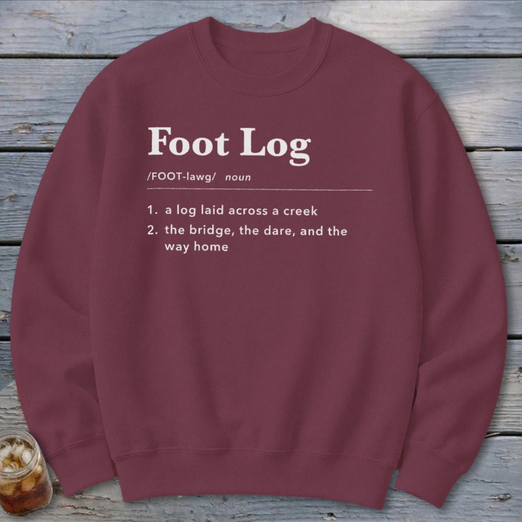 A maroon crewneck sweatshirt with white dictionary-style text defining the term Foot Log.