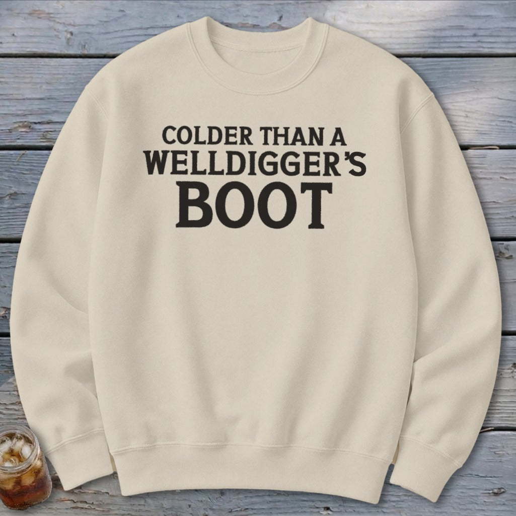 Cream sweatshirt with black text reading "Colder Than A Welldigger's Boot".