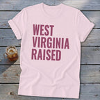 Light pink t-shirt with "WEST VIRGINIA RAISED" text in dark pink.