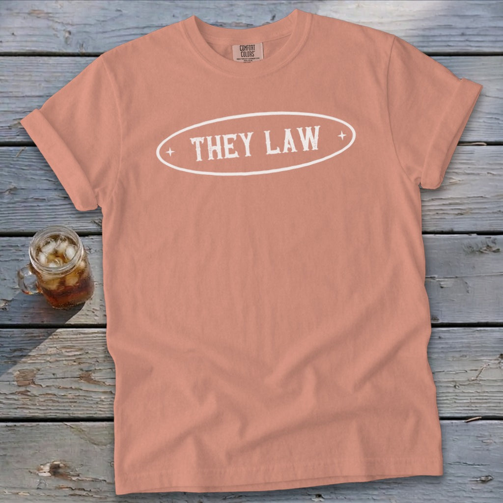 Peach t-shirt with white oval graphic reading "THEY LAW" and Comfort Colors tag.