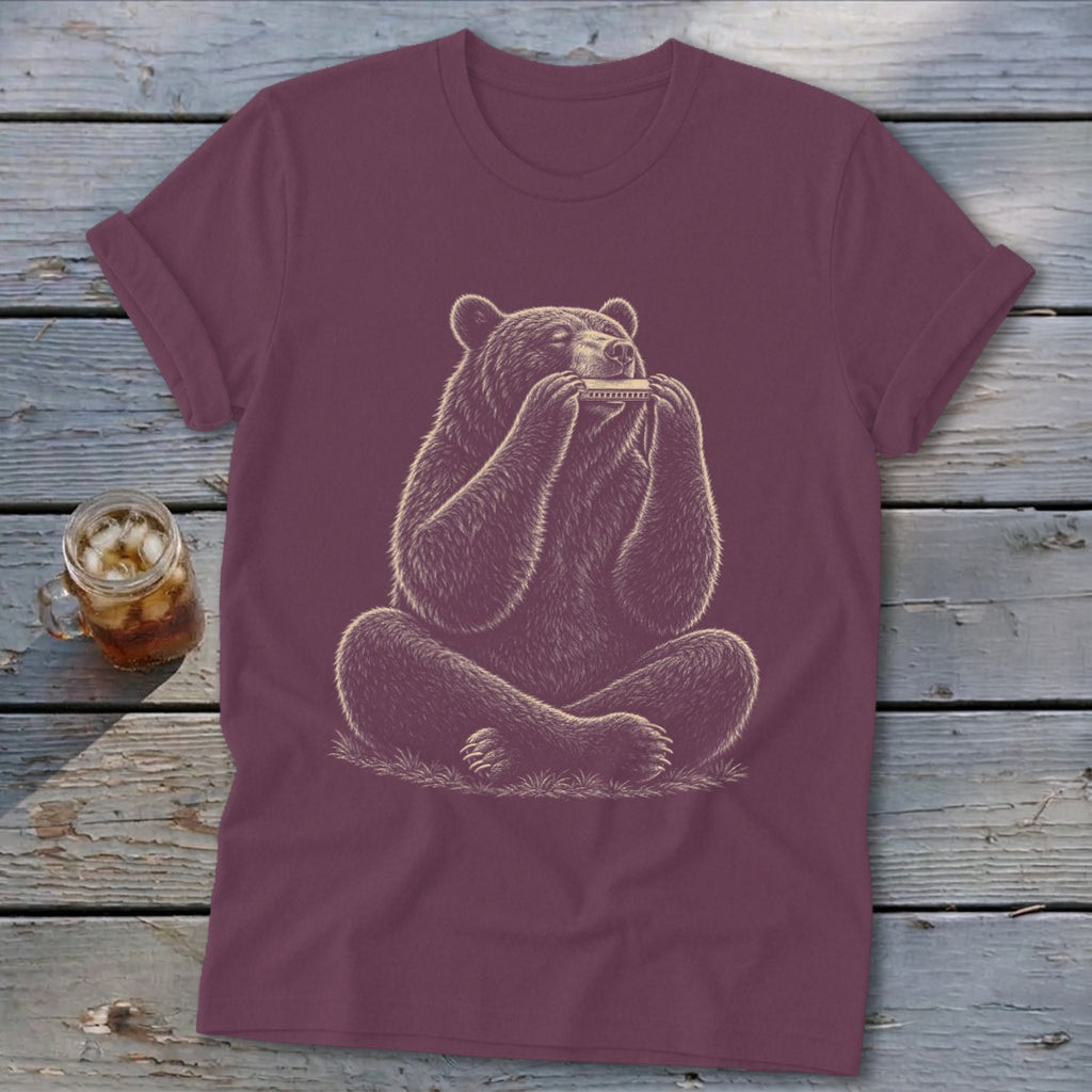Maroon t-shirt with a drawing of a bear playing a harmonica while sitting cross-legged.
