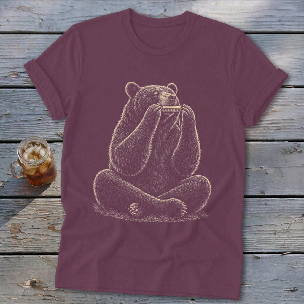 Maroon t-shirt with a drawing of a bear playing a harmonica while sitting cross-legged.