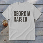 White t-shirt with bold dark gray text that reads "GEORGIA RAISED".