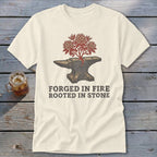 Cream t-shirt with anvil, blooming branches, and text "FORGED IN FIRE ROOTED IN STONE".