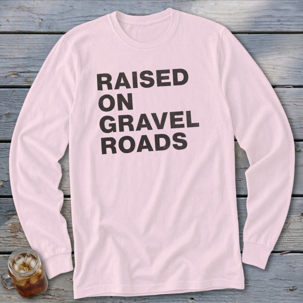 Pink long-sleeve shirt with black text "RAISED ON GRAVEL ROADS".