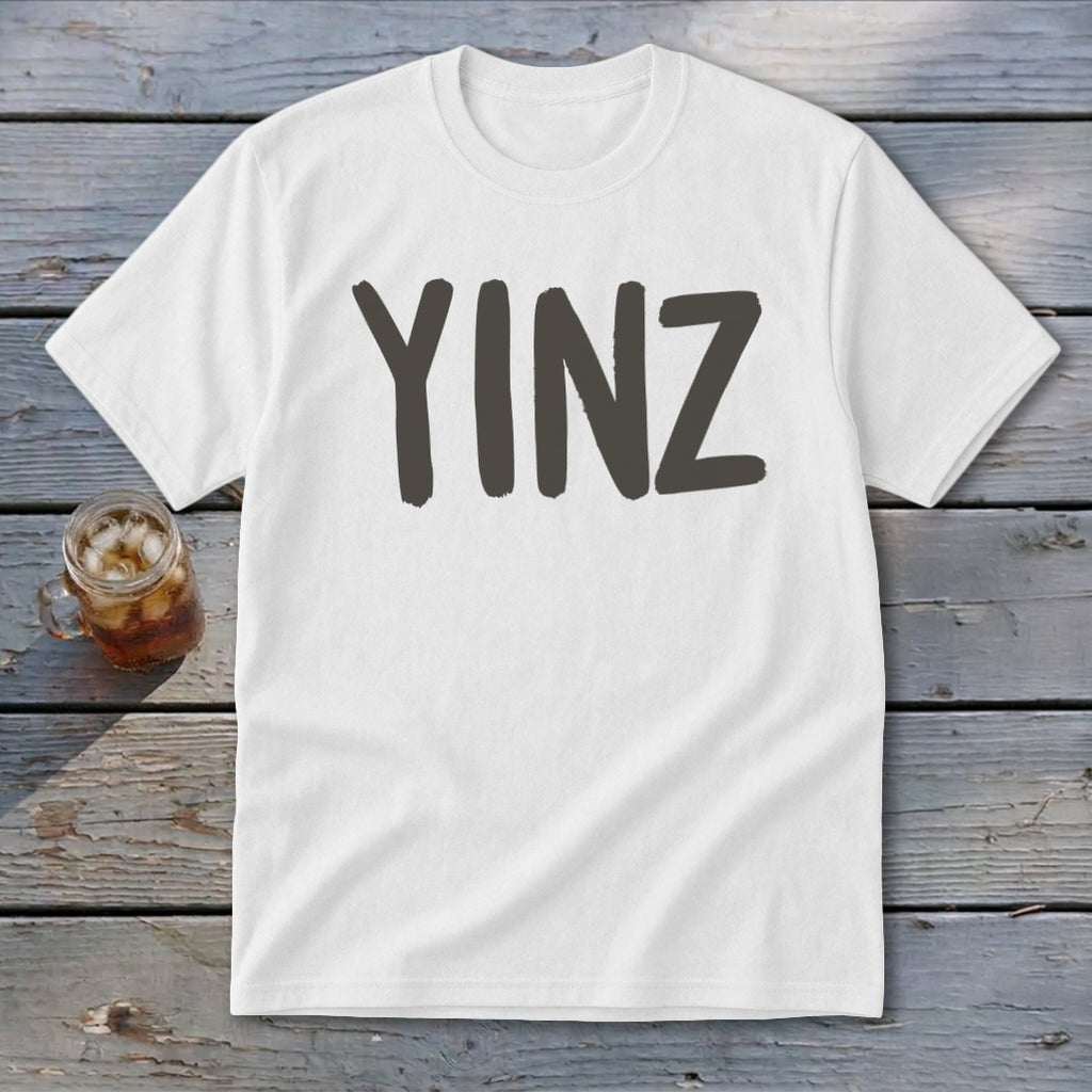 White t-shirt with "YINZ" in dark gray letters, next to a glass of iced tea.