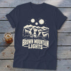 A dark blue t-shirt with a graphic of three figures looking at mountain lights.