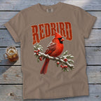 Taupe t-shirt featuring a red cardinal perched on a snowy pine branch with red berries and the text REDBIRD.