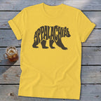 Yellow t-shirt with a brown bear graphic containing the word Appalachia laid flat on a wooden surface.