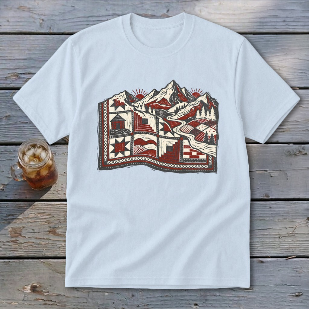 A light blue crewneck t-shirt featuring a red, white, and black graphic of mountains and a quilted landscape.