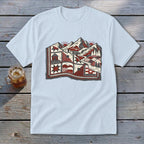 A light blue crewneck t-shirt featuring a red, white, and black graphic of mountains and a quilted landscape.