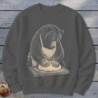 Bear in apron kneading dough on a cutting board.