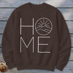 Brown crewneck sweatshirt featuring a white graphic with the word HOME, where the O is replaced by a mountain landscape and sun.