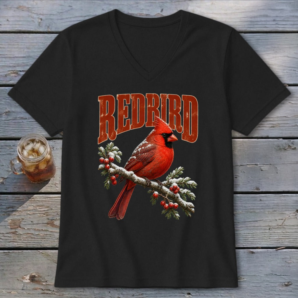 A black V-neck t-shirt features a red cardinal perched on a snow-covered pine branch with the text "REDBIRD".