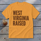 Orange t-shirt with "WEST VIRGINIA RAISED" in brown block lettering.