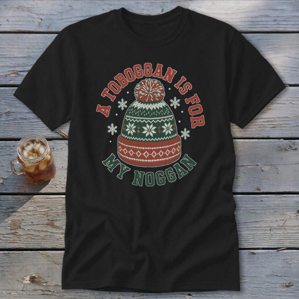A black t-shirt featuring a green, red, and white winter beanie graphic with the text A Toboggan is for My Noggan.