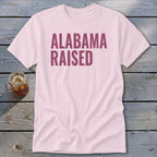 Pink t-shirt with "ALABAMA RAISED" text in maroon.