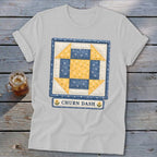 White t-shirt with a blue and yellow patchwork quilt square that says "Churn Dash".