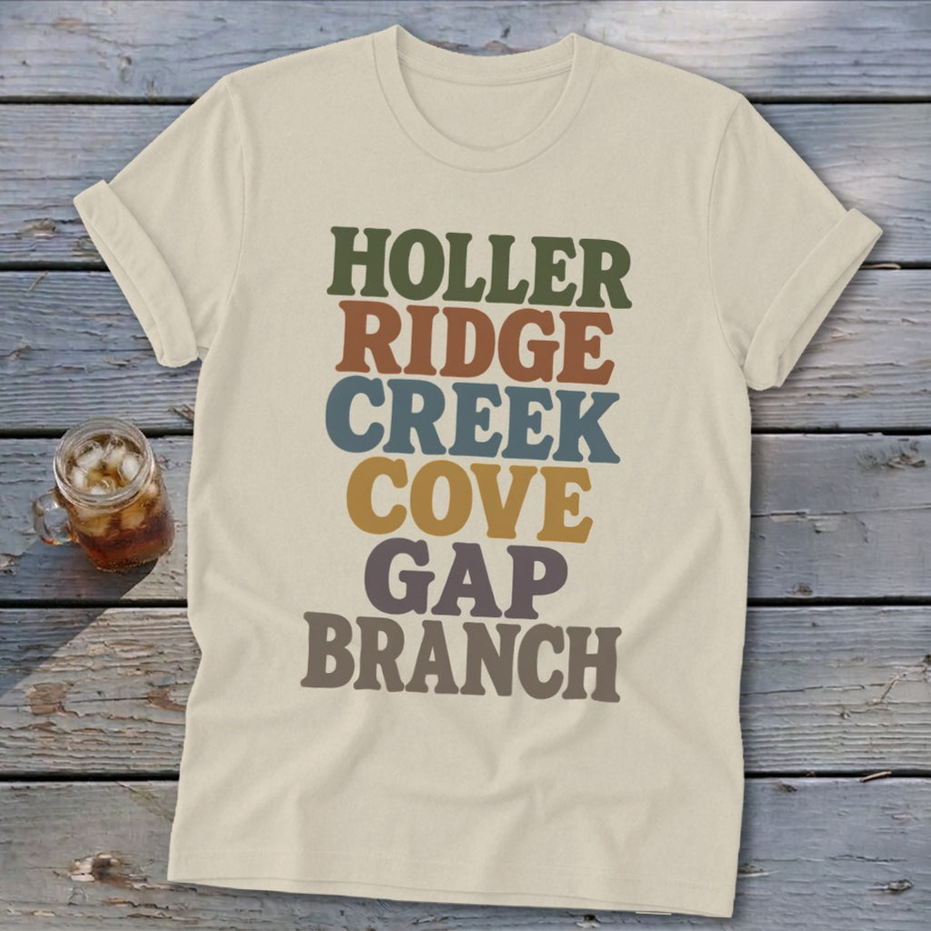Cream t-shirt featuring stacked retro text in green, brown, blue, yellow, and grey on wooden boards.