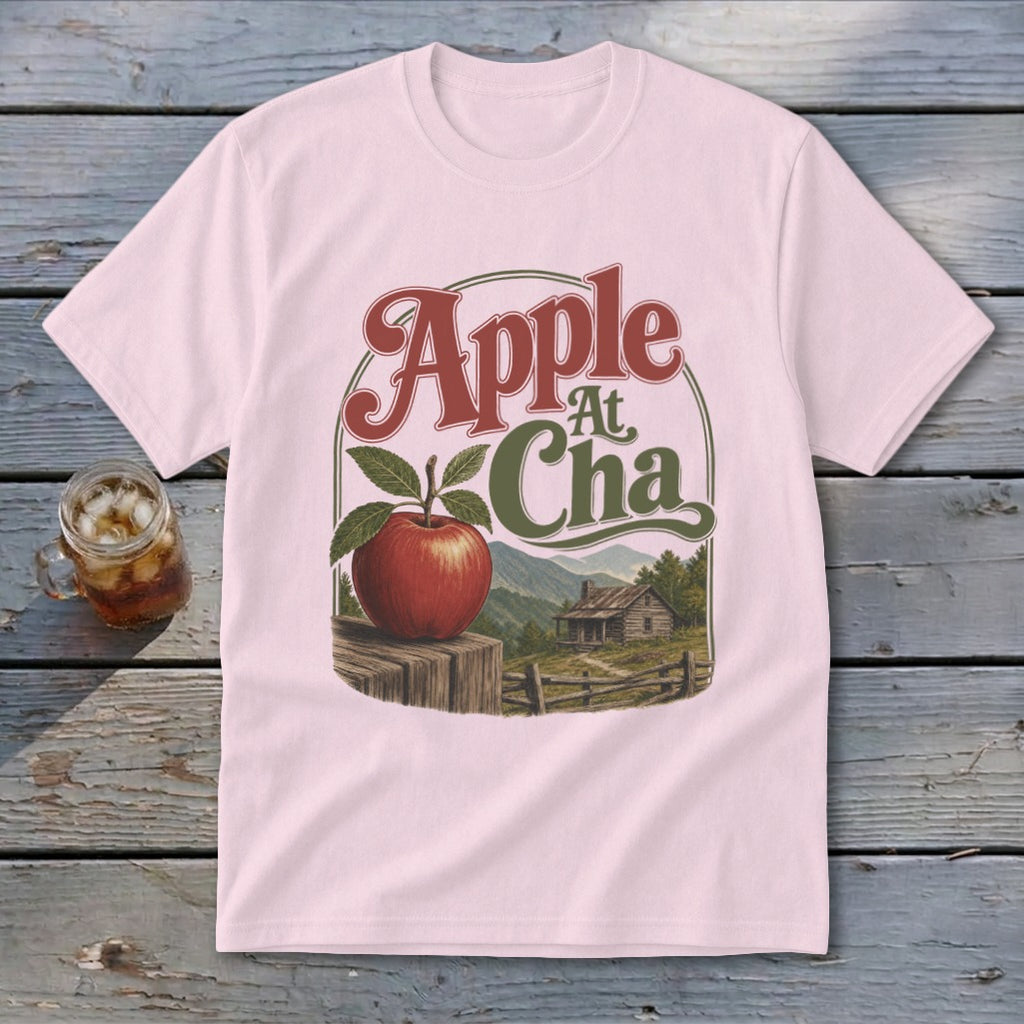Light pink t-shirt with a vintage graphic featuring an apple, cabin, and Apple At Cha text.