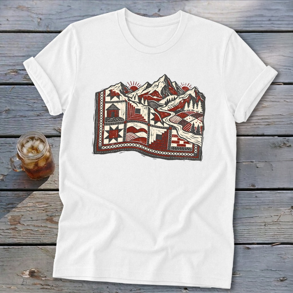 A white t-shirt features a red, black, and white graphic combining a landscape and quilt patterns.