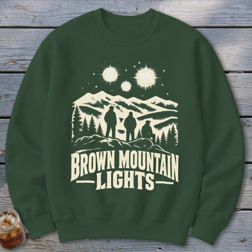 A dark green crewneck sweatshirt featuring a graphic of three figures looking at mountain lights.