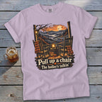 Purple t-shirt with porch scene: rocking chairs, pumpkins, lantern, and text "Pull up a chair. The holler's talkin'."