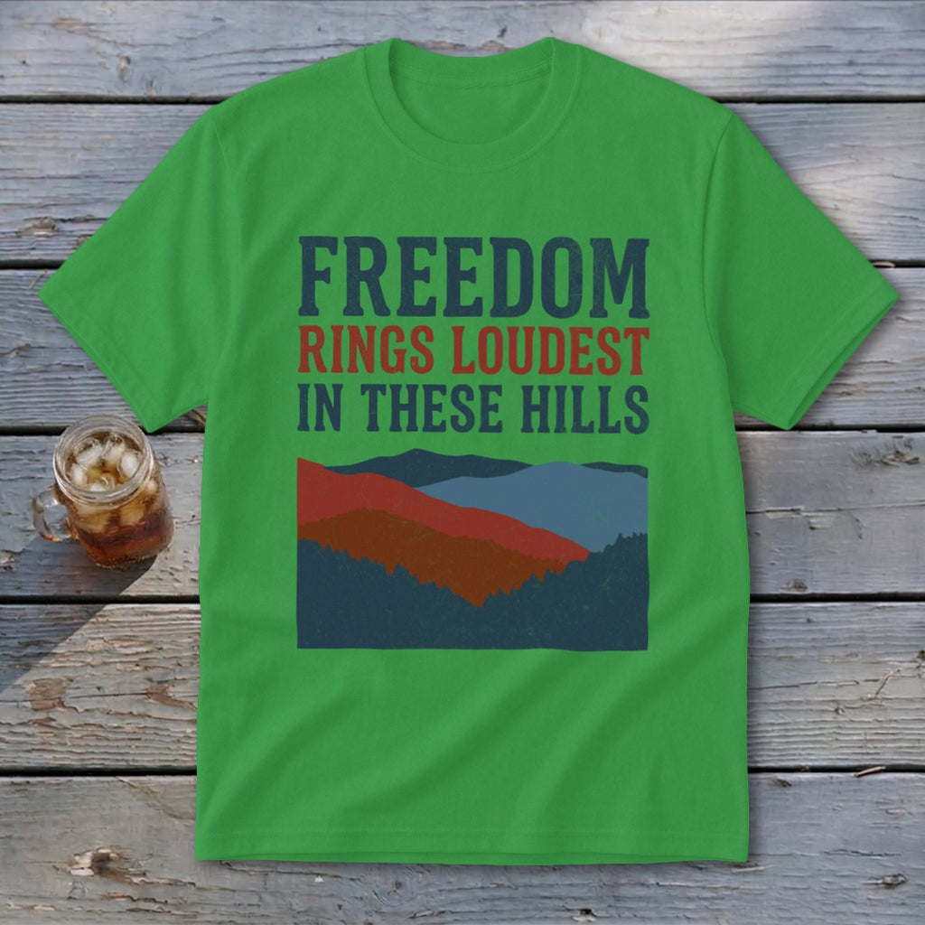 A green t-shirt featuring the text Freedom Rings Loudest In These Hills and a mountain graphic.