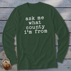Dark green long-sleeve shirt with white text that says "ask me what county i'm from".