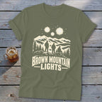 Olive green crewneck t-shirt featuring a graphic of three figures, mountains, stars, and the text Brown Mountain Lights.