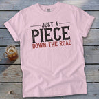 Pink t-shirt with text "JUST A PIECE DOWN THE ROAD"