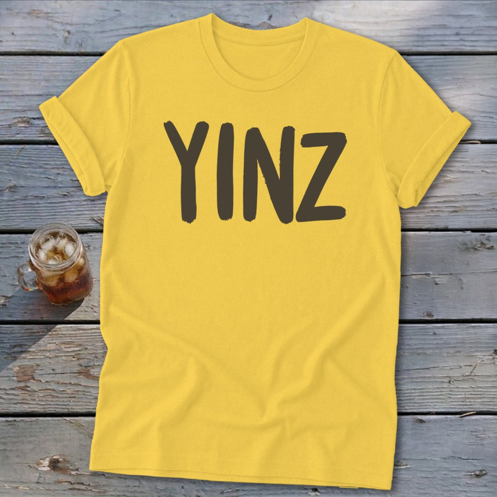 Yellow t-shirt with the word "YINZ" printed in dark brown.