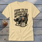 A pale yellow t-shirt with a graphic of a bear relaxing in a rocking chair.